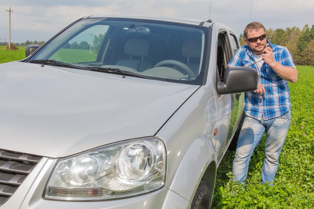 Farmer standing next to a pickup in a field using a walkie talkie